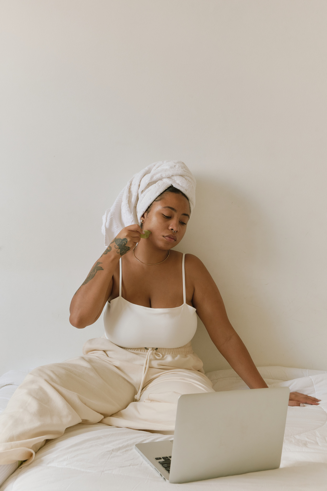 Woman Using Gua Sha While Using Laptop on the Bed